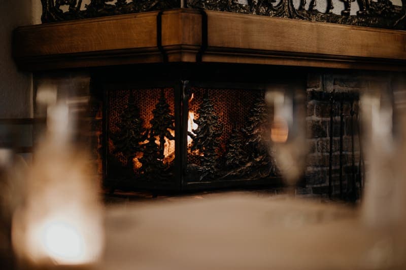 Brennender Kamin mit kunstvollem Metallgitter im Walddesign in rustikalem Veranstaltungsraum