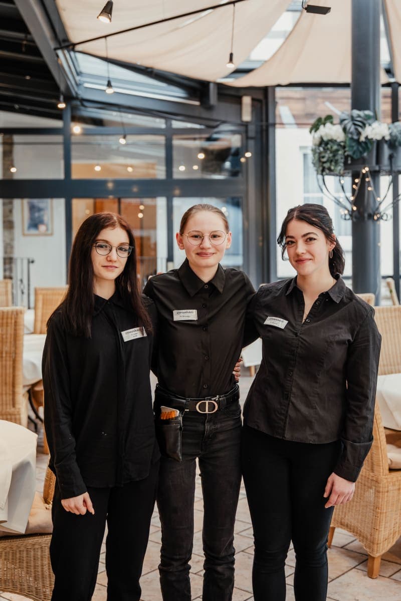 Drei lächelnde Servicemitarbeiterinnen in schwarzer Uniform im Restaurant des Hotel Hoher Hahn
