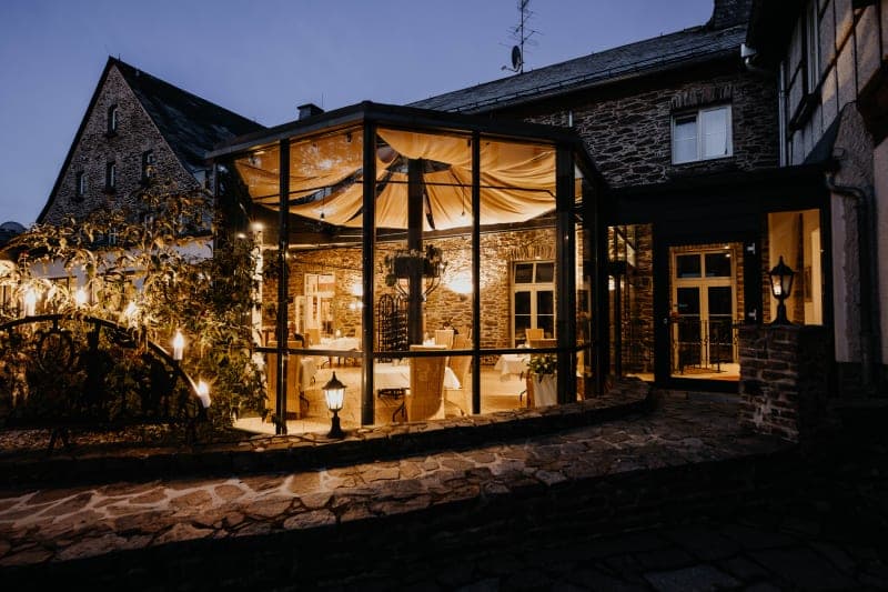 Hotel Hoher Hahn bei Nacht mit beleuchtetem Wintergarten und Schieferfassade