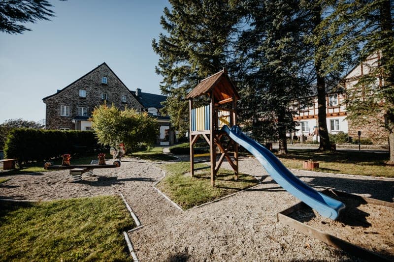 Kinderspielplatz mit Rutsche und Schaukeltieren im Hotelgarten